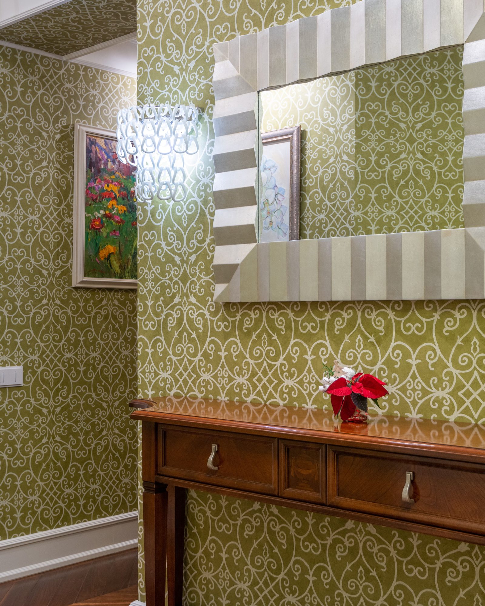 Traditional hallway with olive green scroll-pattern wallpaper, a striped silver mirror, and a mahogany console